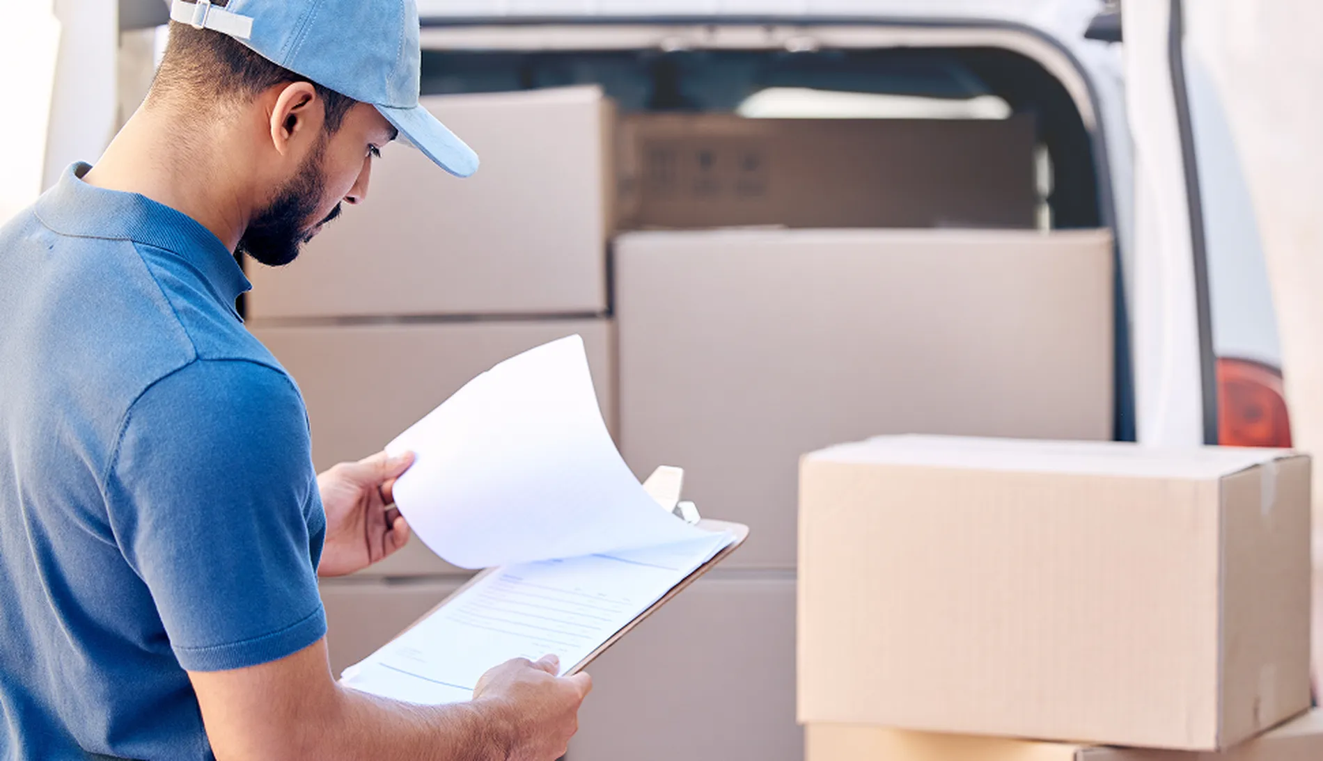 courier driver checking schedule during multi drop driving route with van loaded with packages in the background-02